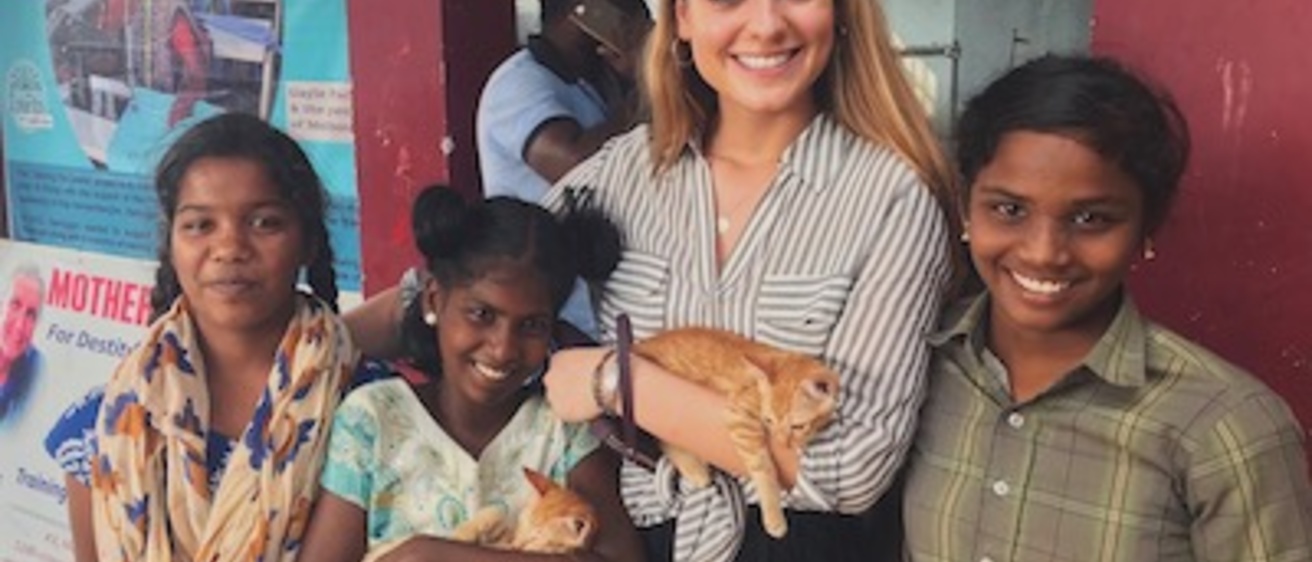 woman smiles with children and cat in India