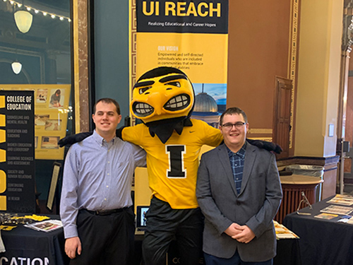 People pose with University of Iowa mascot at a caucus event.
