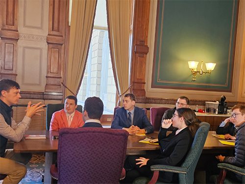 Iowa State Auditor Rob Sand and members of the UI REACH student council sit together at a table