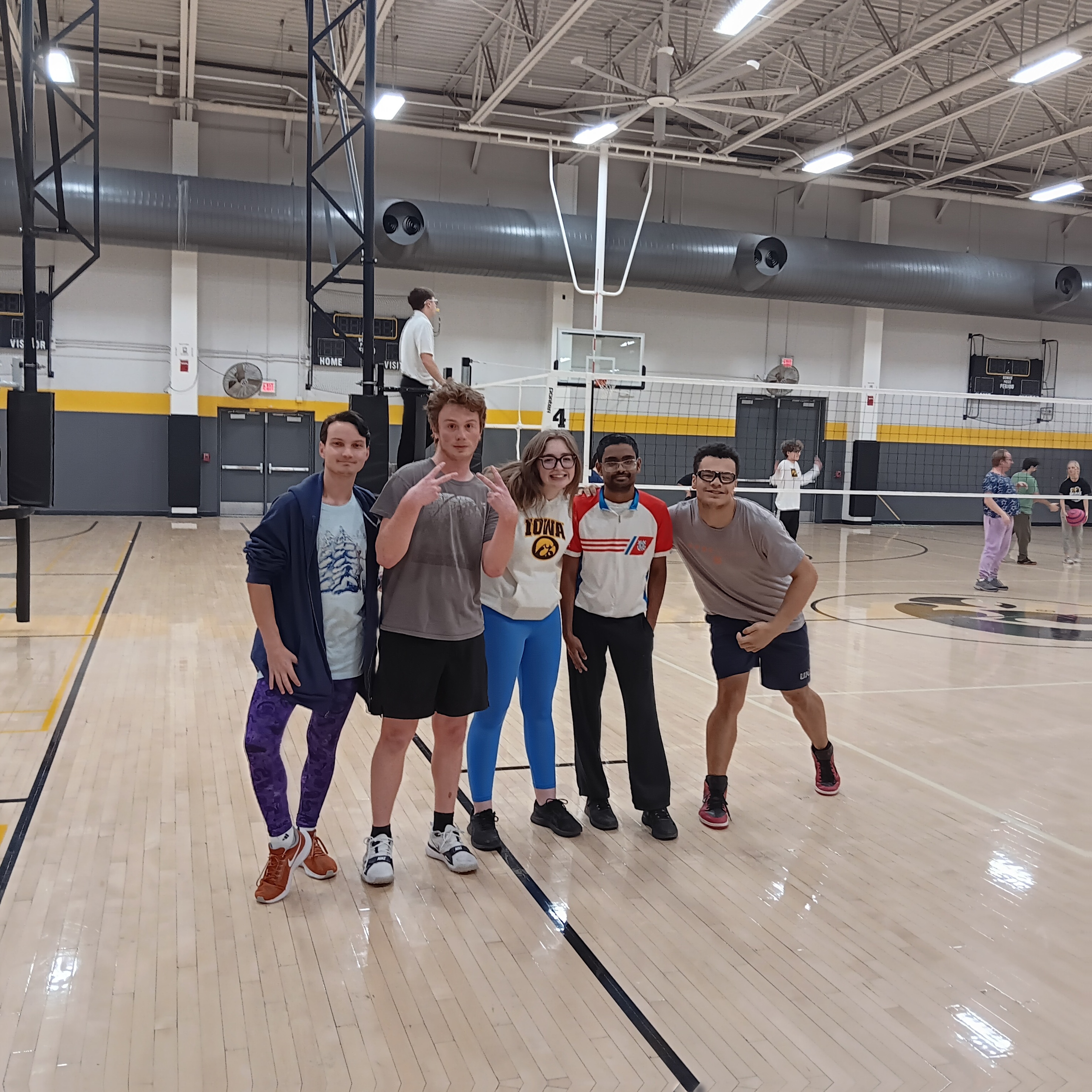 students standing on an indoor volleyball court.