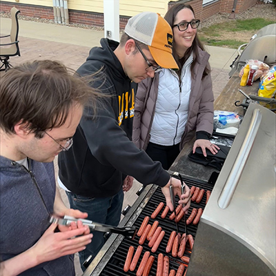 Students grill hotdogs outside.