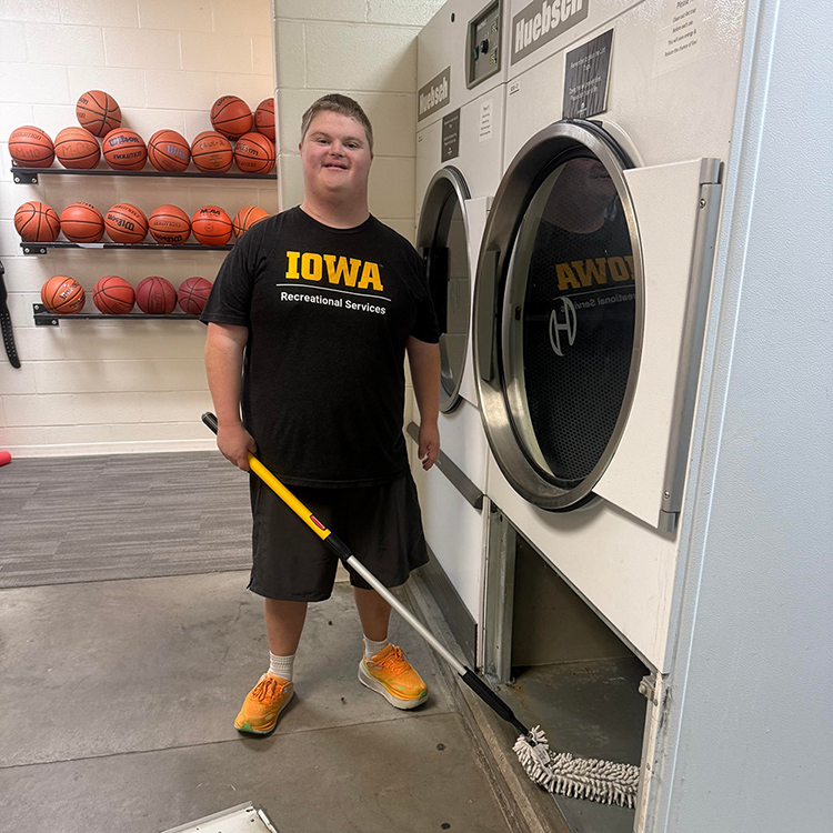 student cleans underneath a dryer at the Campus Recreation and Wellness Center.