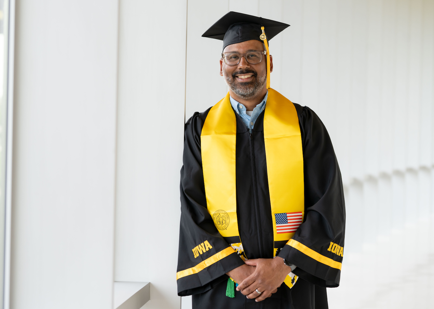 Man in graduation robes smiles