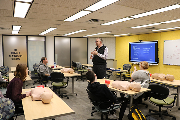 An instructor teaches CPR to a classroom of students.