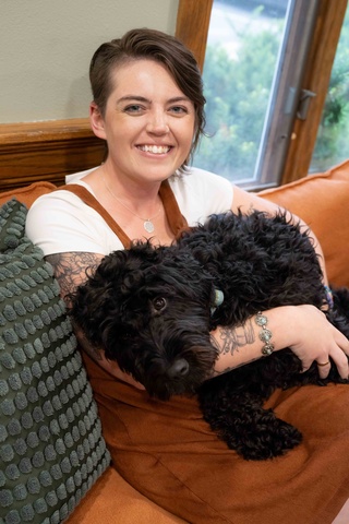 woman holds dog as she sits on couch