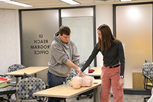 Avari Everts and a UI REACH student practice CPR on a CPR manikin