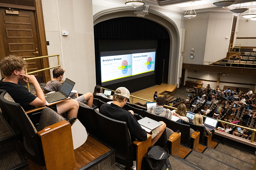 Students sit in a lecture hall auditorium.
