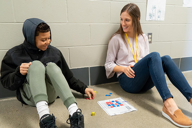 Young boy playing math game with student teacher