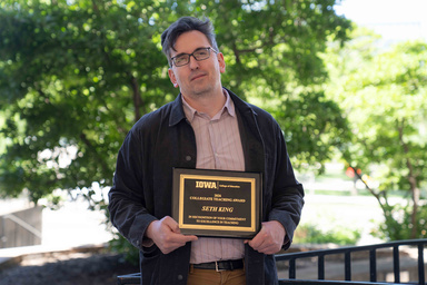 Seth King holds his Collegiate Teaching Award plaque