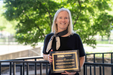 Megan Foley-Nicpon stands with her Collegiate Teaching Award plaque