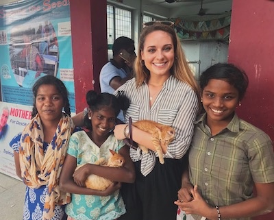 woman smiles with children and cat in India