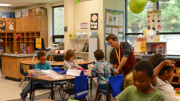 Young man works with elementary students
