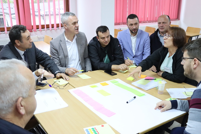 Faculty and staff gather around a table for a training session in Kosovo.