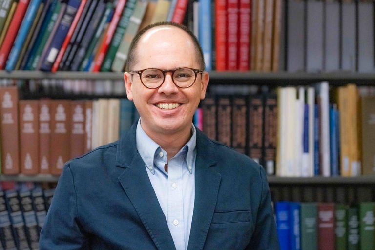 Shawn Datchuk stands in front of a bookcase