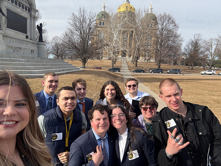 A group of students and staff stand in front of the Capitol Building.