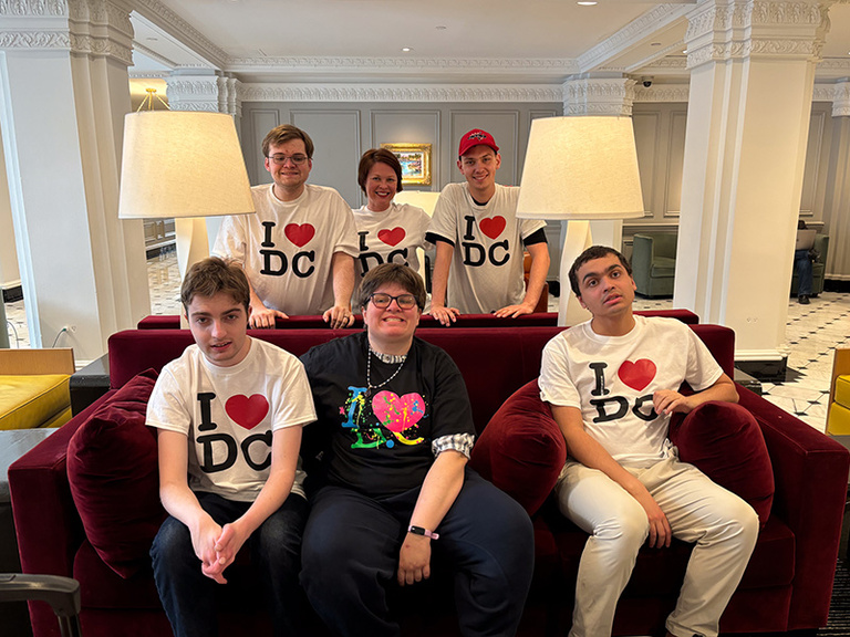 Students and a staff member gathered around a couch wearing matching I love D.C t-shirts.