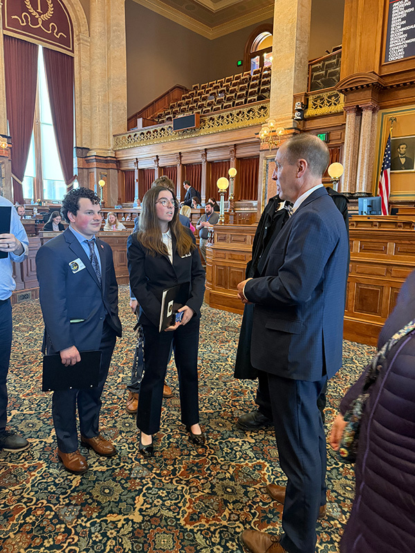 Two students and a state representative stand together and talk.