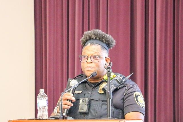 Alton Poole stands at a podium, holding a microphone.