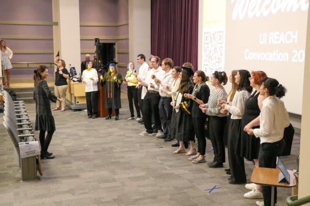 The Heavenley Hawkeyes Choir sings in front of an auditorium as Professor Hae Sun Kim conducts.