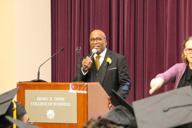 Bill Lloyd stands at a podium, holding a microphone.