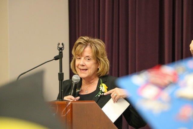 Barbara Wilson stands at a podium, holding a microphone.