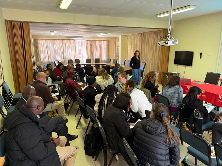 Group of people sitting in classroom setting as woman lectures