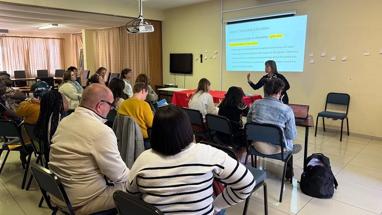 Woman stands in front of screen, lecturing