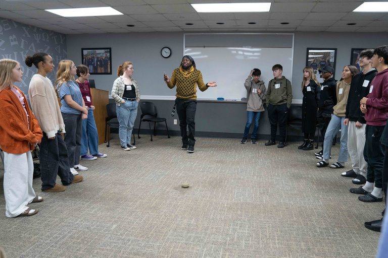 Students gather in large circle around one man talking