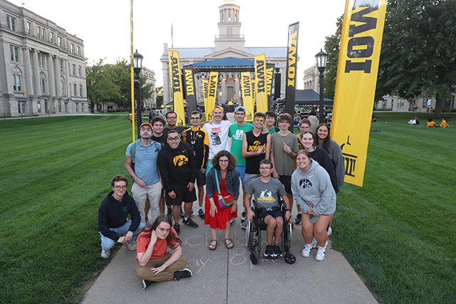 A group of students stand together in front of the Old Capitol building.