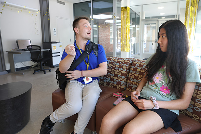 Two students chat with each other in a residence hall lobby.