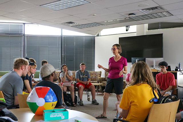 A teacher talks to students playing a game.