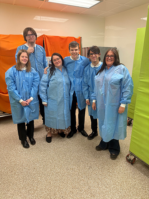 A group of students wear blue lab coats in the Office of Animal Resources.