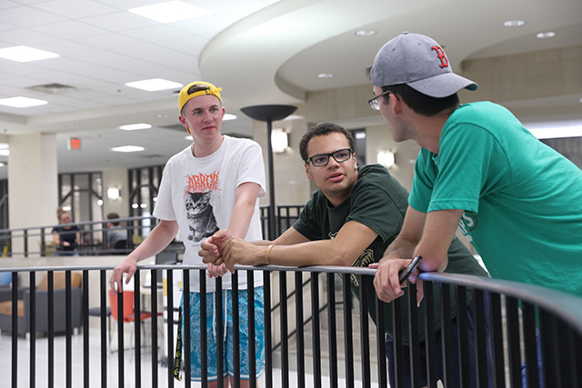Three students chat with each other in a residence hall lobby.