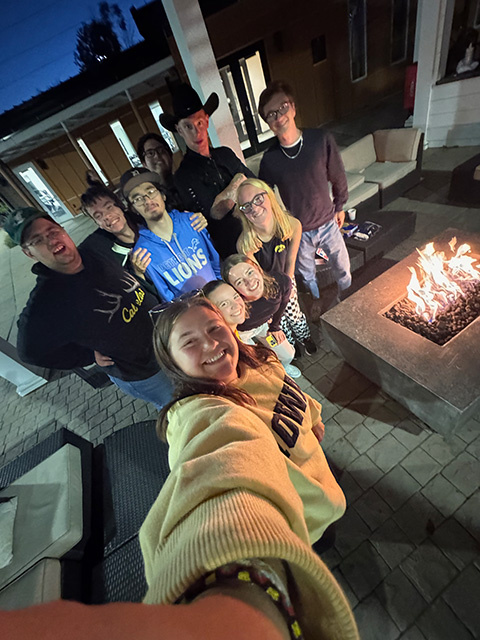 Students and a mentor group together near a bonfire during s’mores night.