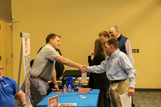 A student shakes hands with an employer at a career fair.