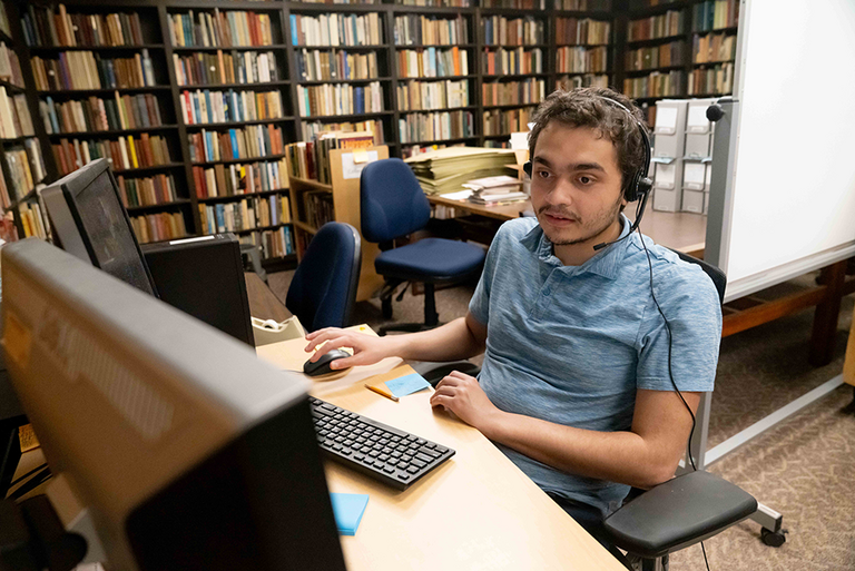 A UI REACH student work on the computer in the library's special collections.