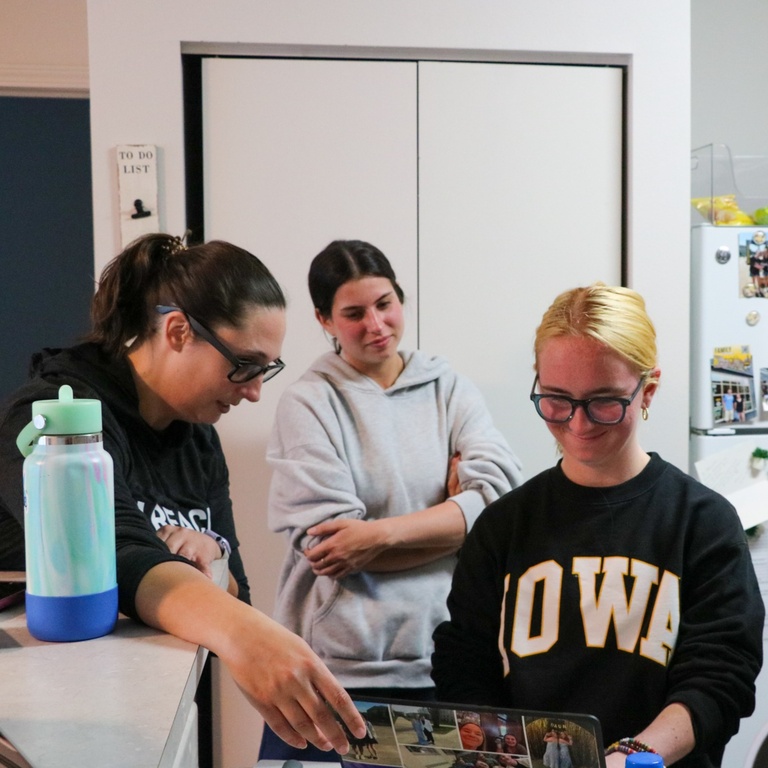 A UI REACH staff member, mentor, and student look at a laptop