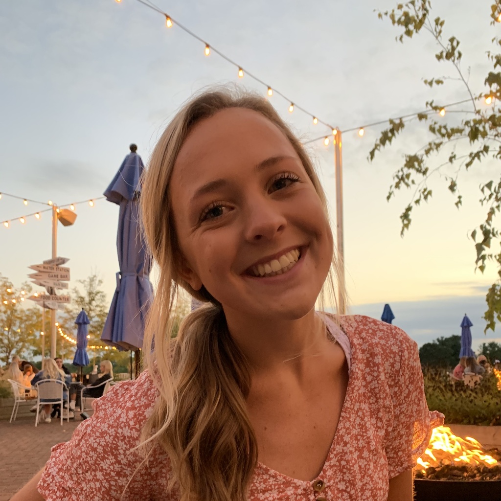Young woman smiles in front of a sunset