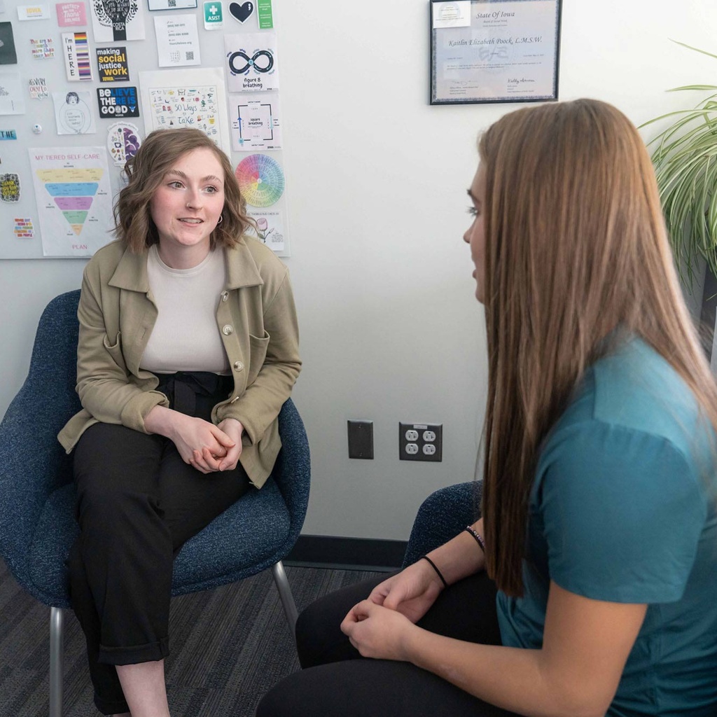 two women sit, talking