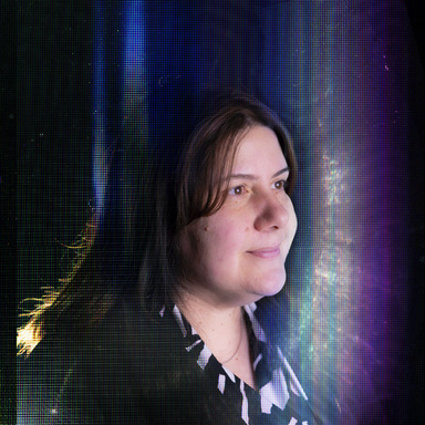 Woman smiles surrounded by shimmering rainbows