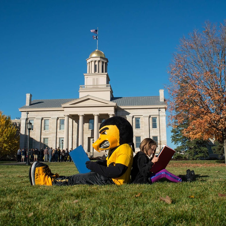 Herky and kid reading on the Pentacrest
