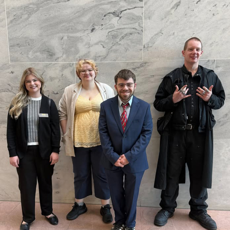 Four students standing in front of a wall.