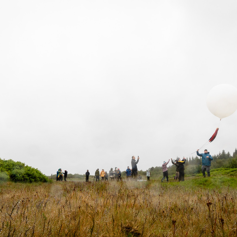 Students and faculty help guide the balloon as it starts to ascend