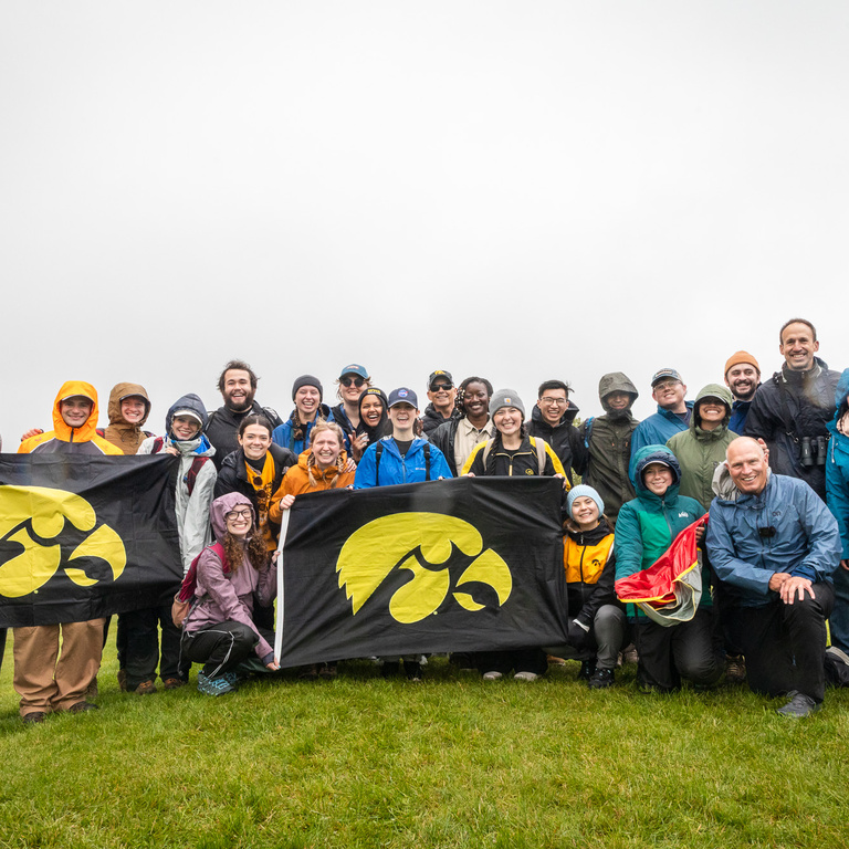 The entire interdisciplinary team, outside, smiling with Hawkeye flags after a successful launch.