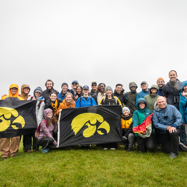 The entire interdisciplinary team, outside, smiling with Hawkeye flags after a successful launch.