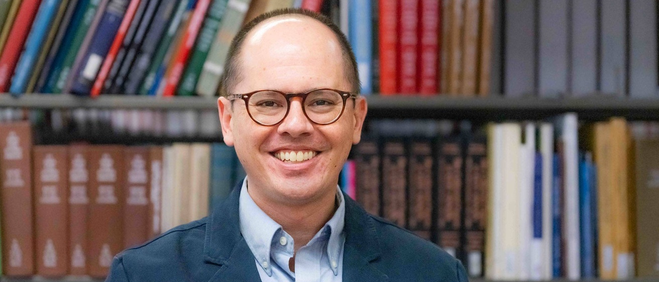 Shawn Datchuk stands in front of a bookcase