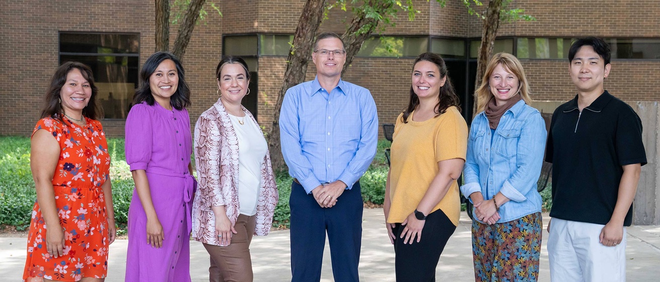 Seven newly appointed faculty stand in front of Lindquist 