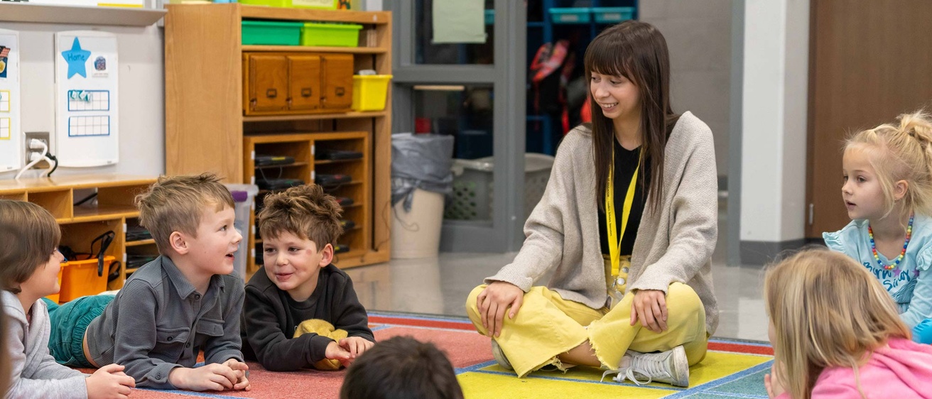 COE Student Lily Prochaska sits with a group of elementary students 