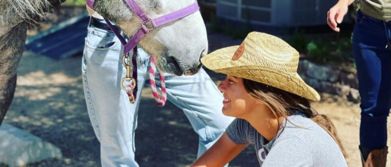 Woman crouches next to horse