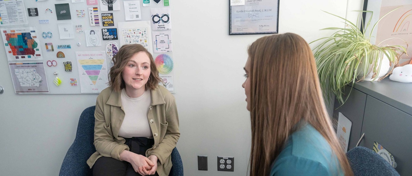 two women sit, talking